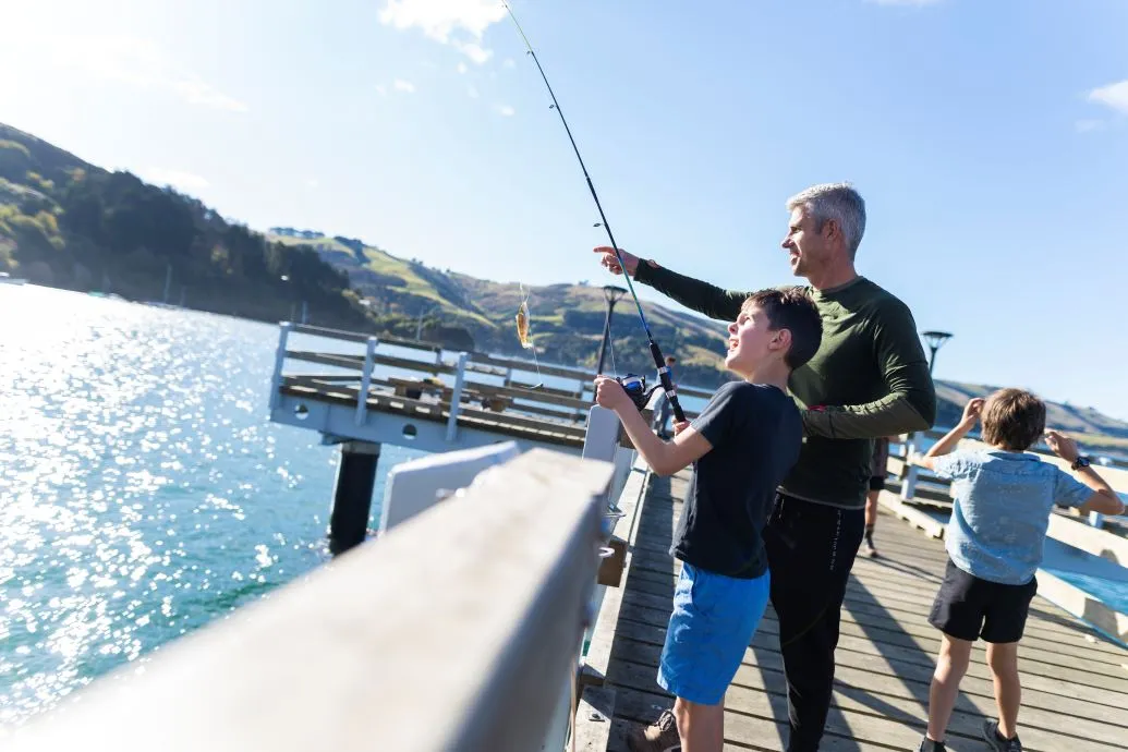 A father and son fishing at a wharf.