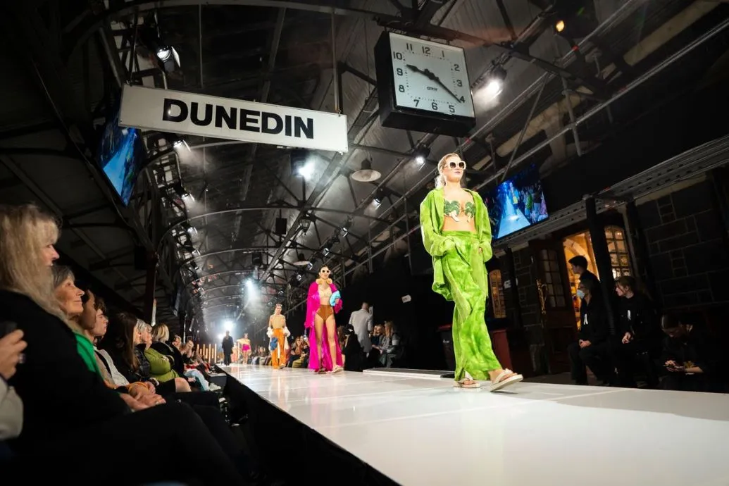 Models in brightly coloured clothing walk the iD Dunedin Fashion Show runway at the Dunedin Railway Station platform.