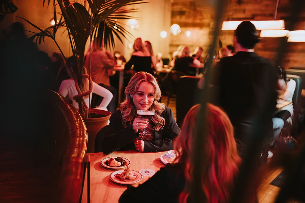 A woman raises her cocktail at Graze and Glow. 