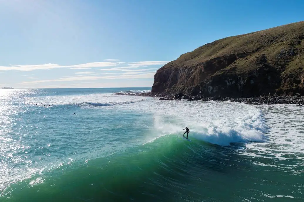 A surfer catches a wave at Whareakeake Beach.