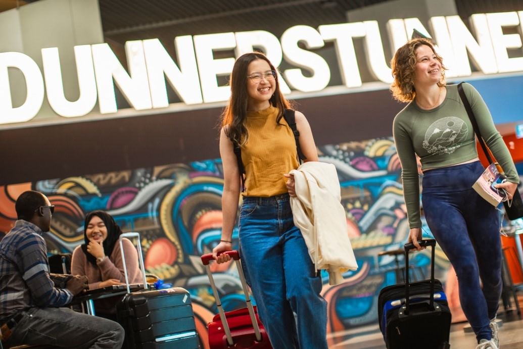 Two women with luggage arrive at Dunedin Airport.